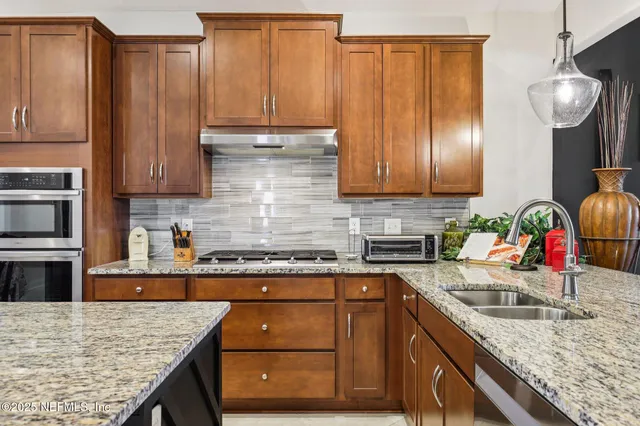 a kitchen with granite countertop a table chairs stove and microwave