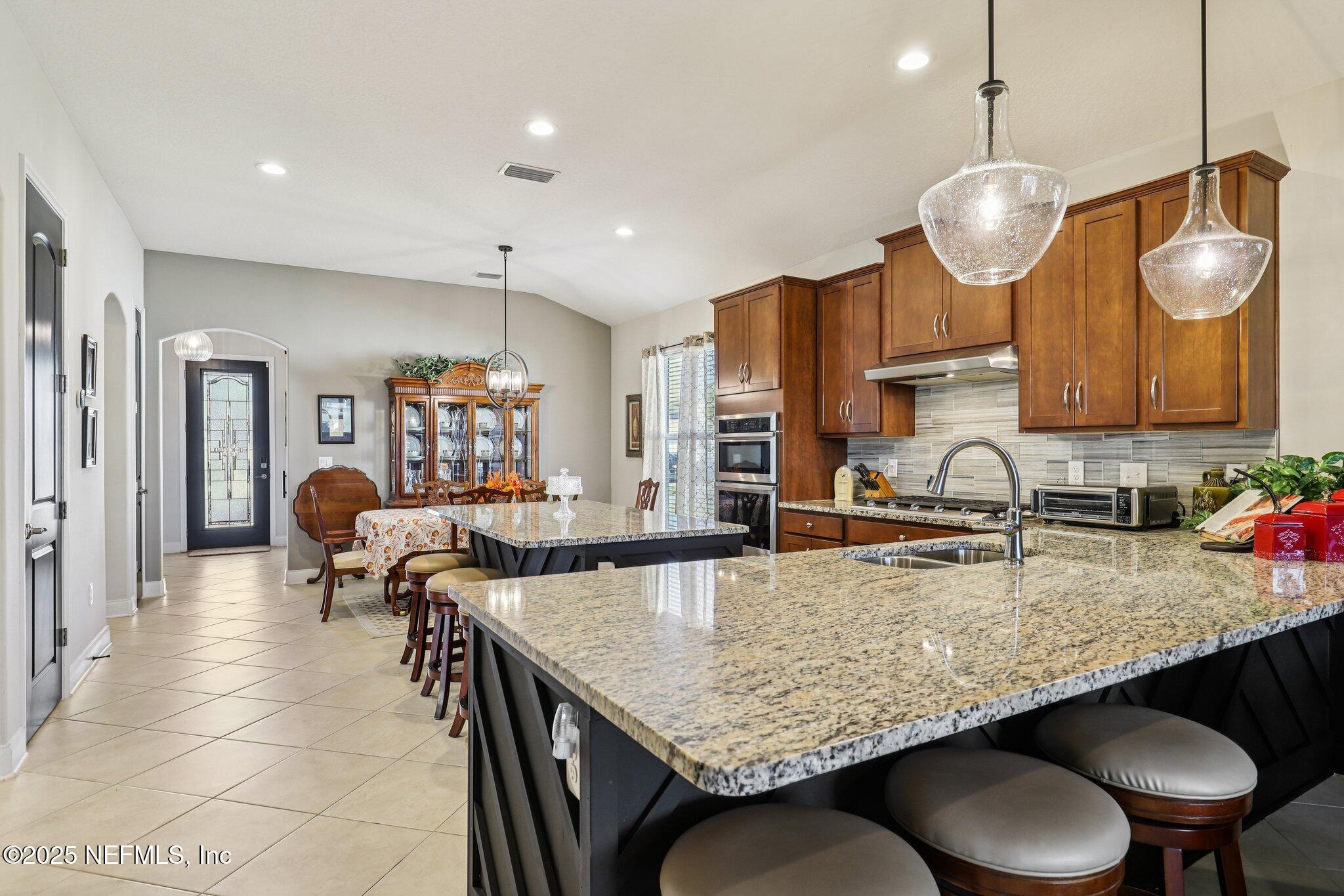 48 Fawn Field Lane St. Augustine, FL 32092 - Photo 21 of 73 a kitchen with granite countertop a table chairs stove and microwave