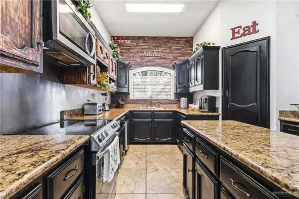 a kitchen with stainless steel appliances granite countertop a stove a sink and a microwave