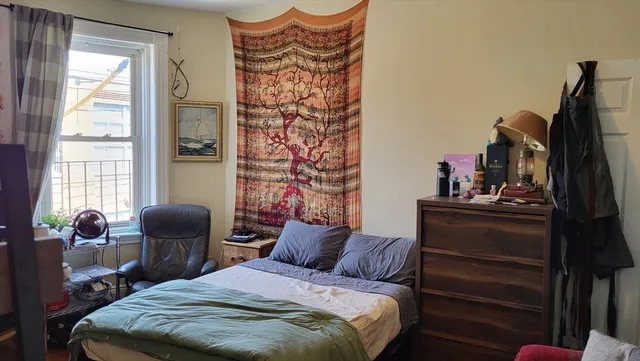 a bedroom with a bed and a chair with the bookshelf