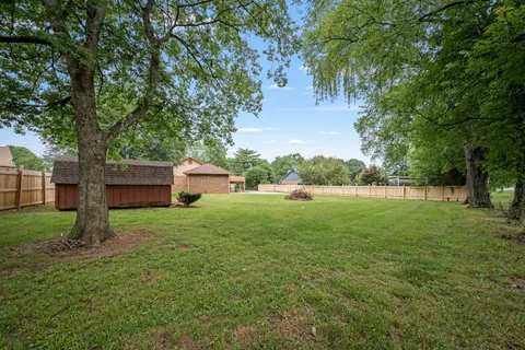 a brick house with a yard plants and large tree