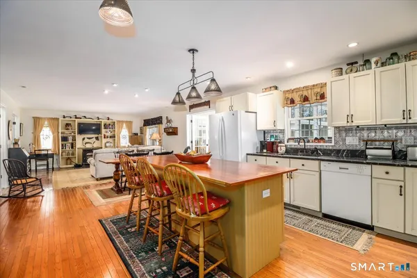 a very nice looking kitchen with granite countertop a stove a sink a dining table and chairs