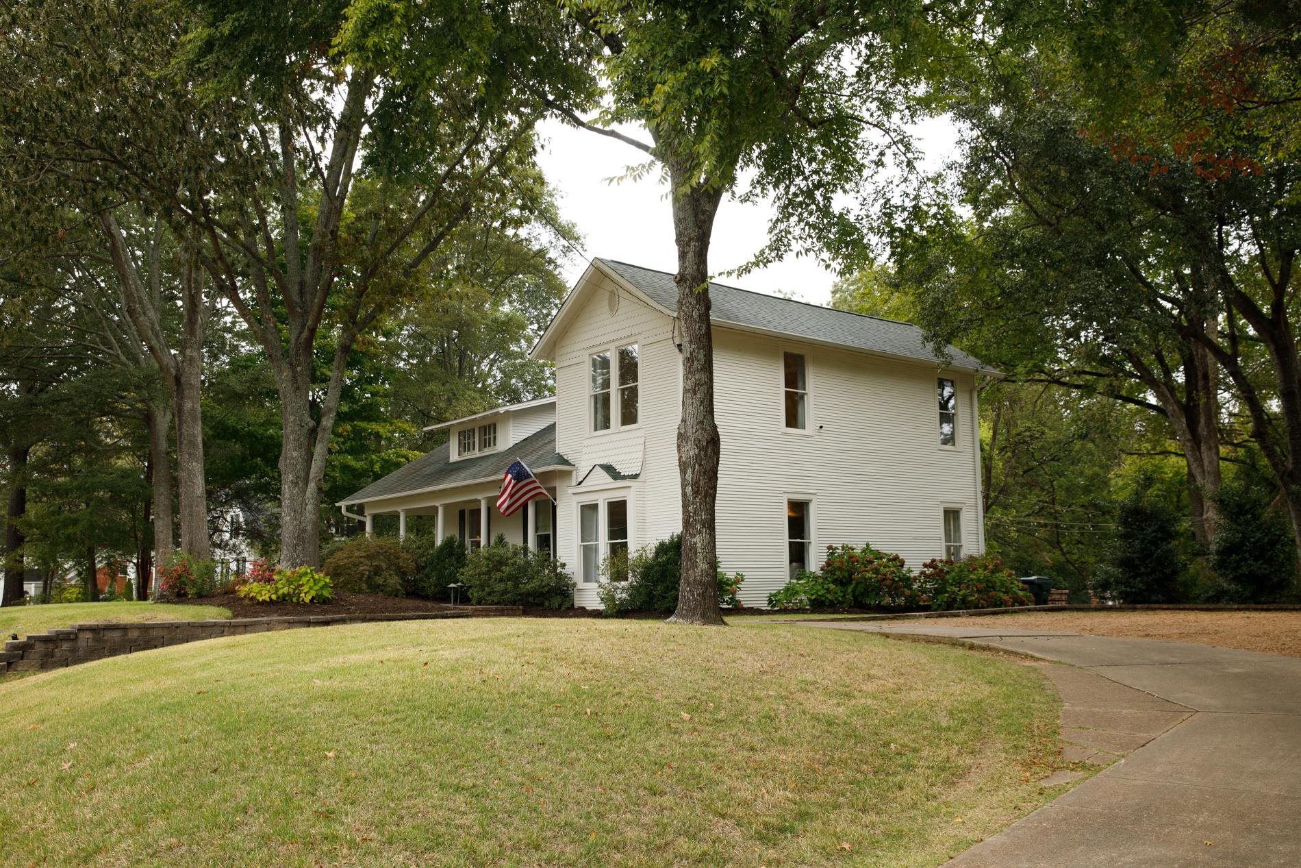232 West Poplar Avenue Collierville, TN 38017 - Photo 3 of 36 View of front of property featuring a front yard, a porch, driveway, and view of wooded area