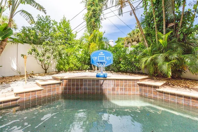 a palm tree sitting in the grass next to a yard