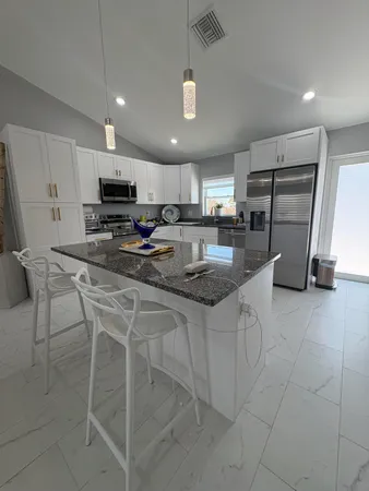 a kitchen with kitchen island granite countertop a stove a sink a microwave and a refrigerator