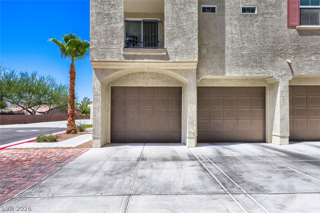2555 Hampton Road, Unit 9301 Henderson, NV 89052 - Photo 25 of 36 A striking facade presents multiple garages, a second-story balcony, and a towering palm.