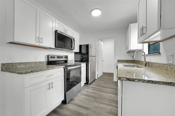 a kitchen with stainless steel appliances granite countertop a sink stove microwave and refrigerator