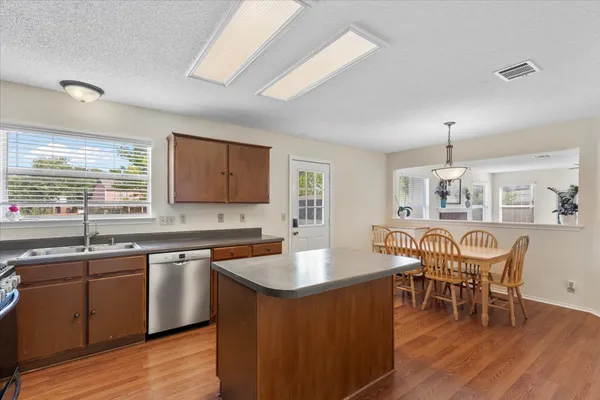 a kitchen with stainless steel appliances granite countertop a table chairs sink refrigerator and cabinets