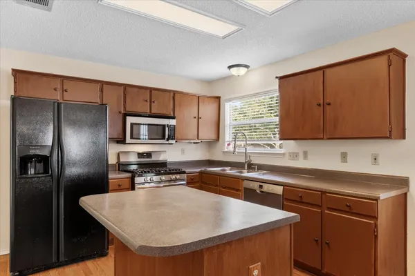 a kitchen with stainless steel appliances granite countertop a sink stove microwave refrigerator and cabinets