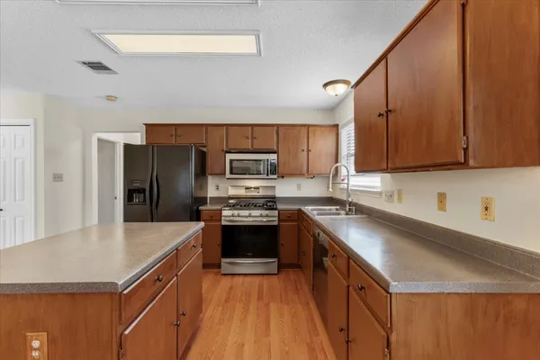 a kitchen with stainless steel appliances a sink dishwasher stove refrigerator and microwave