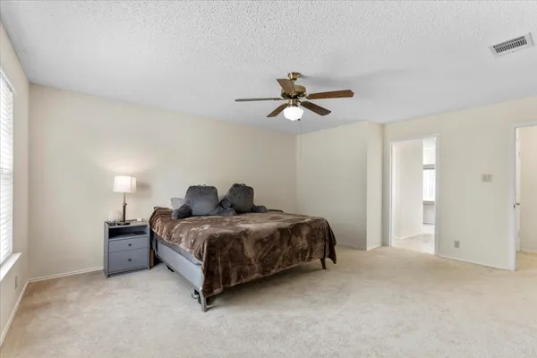 a spacious bedroom with a bed and a ceiling fan