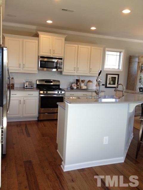 925 Wildflower Ridge Road Wake Forest, NC 27587 - Photo 11 of 24 a kitchen with stainless steel appliances granite countertop a sink dishwasher a stove and white cabinets with wooden floor