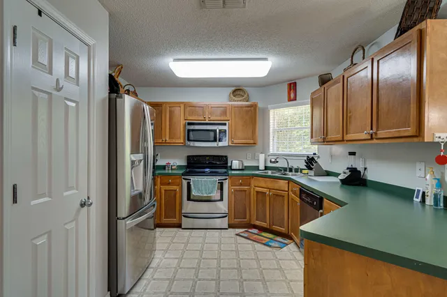 a kitchen with stainless steel appliances granite countertop a refrigerator a stove top oven a sink and dishwasher