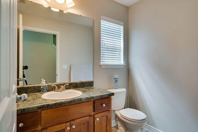 a bathroom with a granite countertop sink toilet and mirror