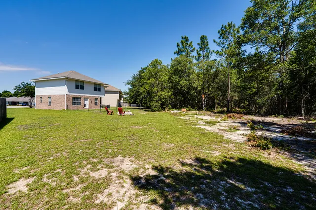 a view of a house with a big yard and large trees