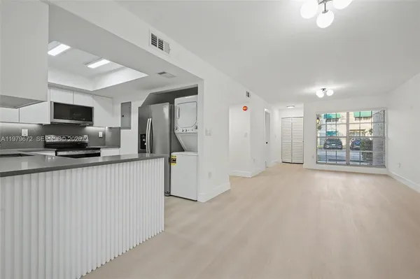a view of a kitchen with a sink and dishwasher a refrigerator with white cabinets