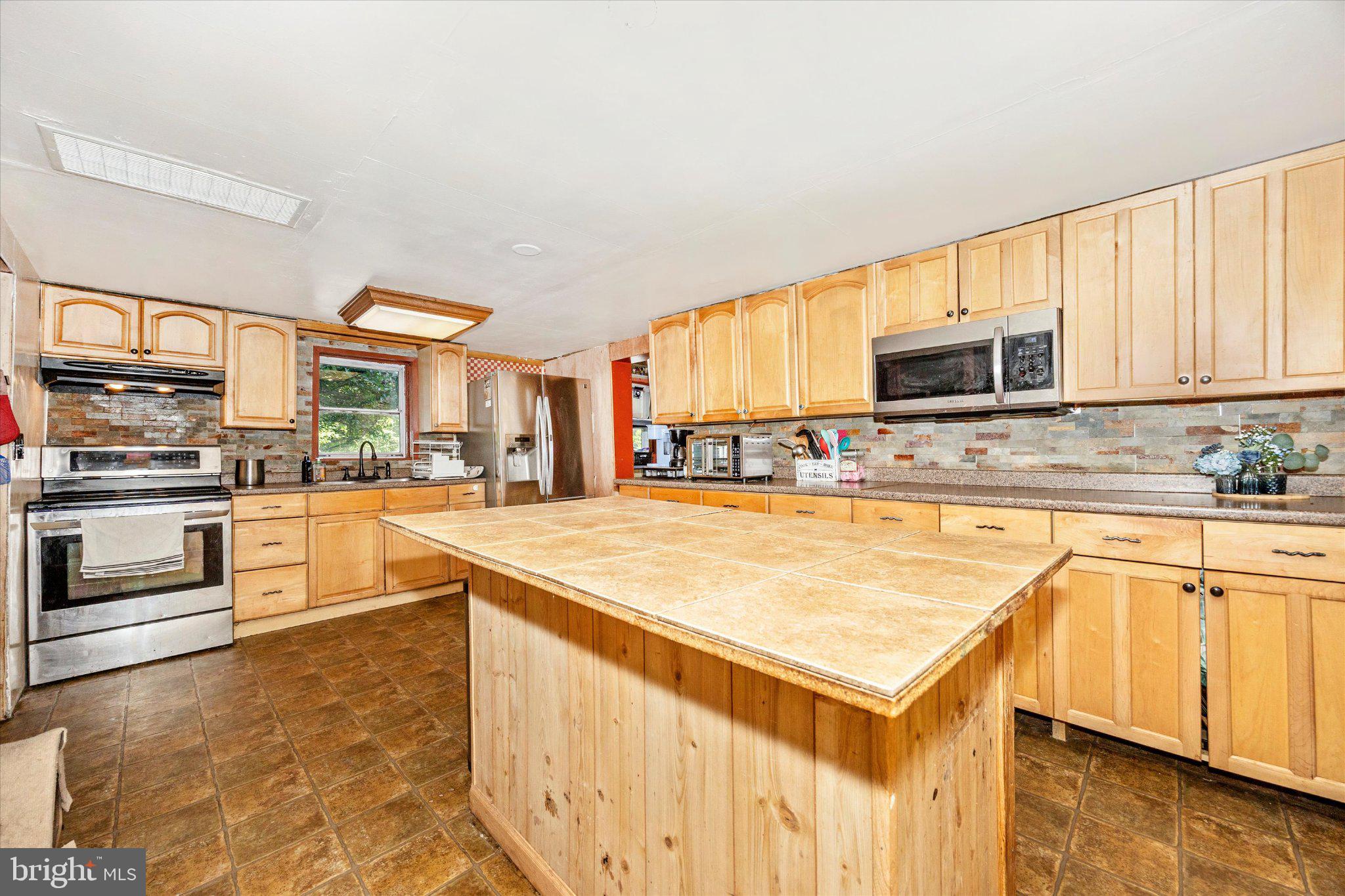 14721 Albert Staub Road Thurmont, MD 21788 - Photo 5 of 46 a kitchen with kitchen island granite countertop a stove top oven a sink dishwasher and white cabinets with wooden floor
