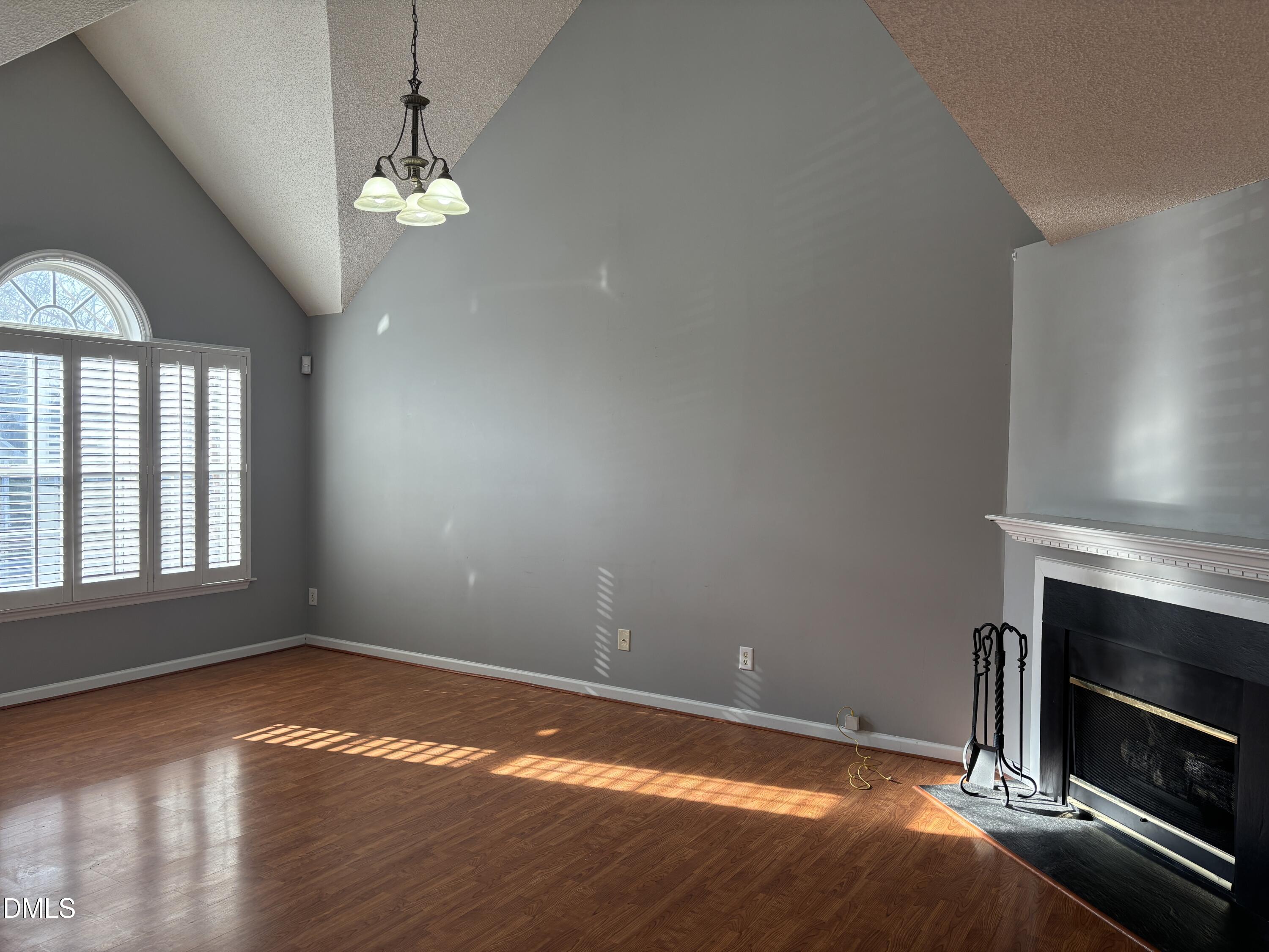 1704 Crag Burn Lane Raleigh, NC 27604 - Photo 6 of 22 an empty room with wooden floor fireplace and windows