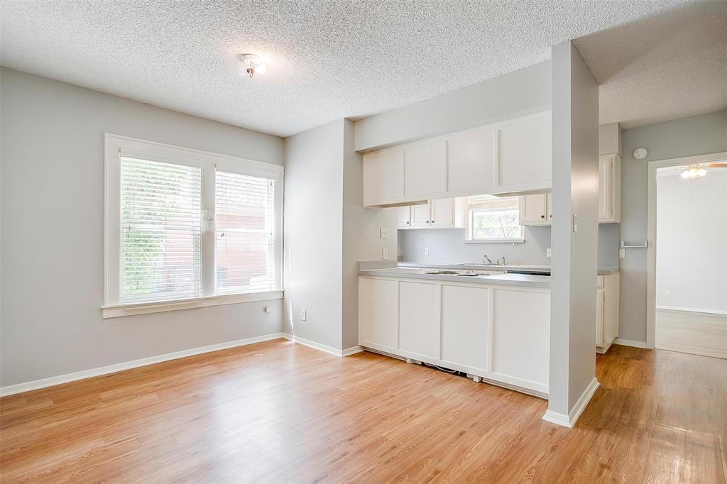 3140 Rogers Avenue, Unit 3142 Fort Worth, TX 76109 - Photo 6 of 13 a kitchen with granite countertop white cabinets and wooden floor