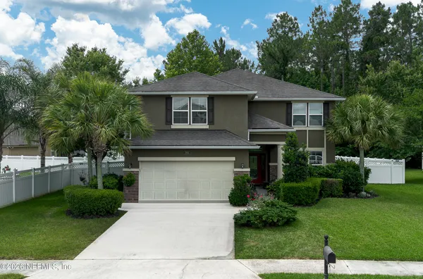 a front view of a house with a yard and trees