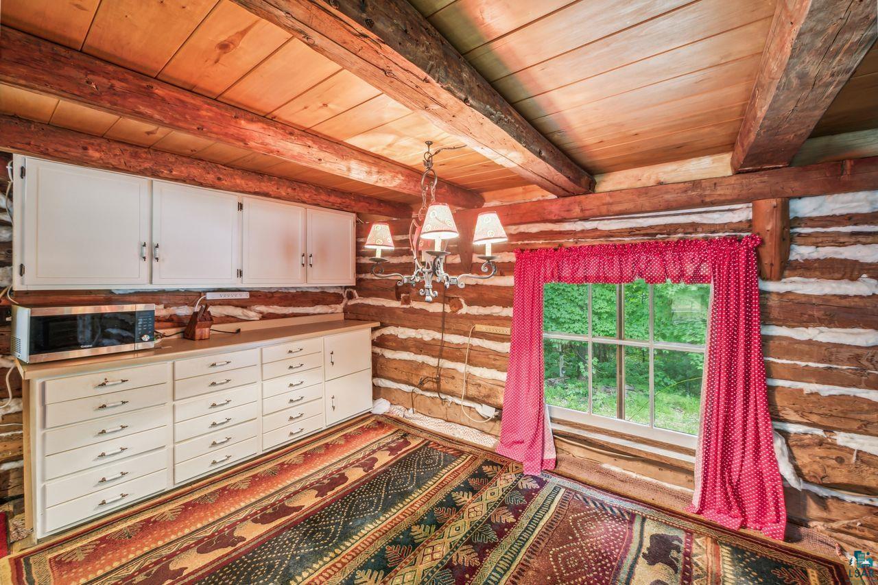 55675 Ashland Bayfield Road Mason, WI 54856 - Photo 5 of 26 Interior space featuring beam ceiling, wood ceiling, hanging light fixtures, log walls, and white cabinetry