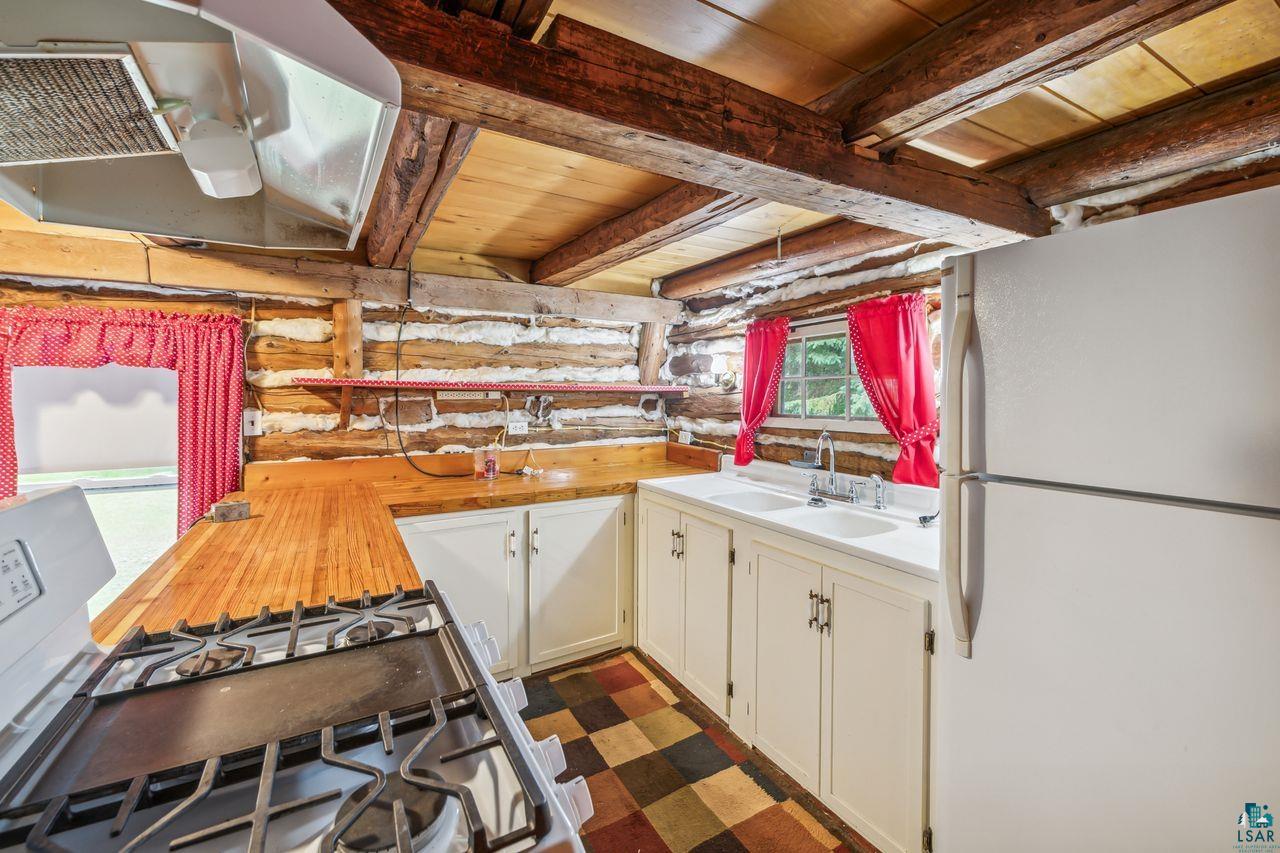 55675 Ashland Bayfield Road Mason, WI 54856 - Photo 6 of 26 Kitchen with log walls, white refrigerator, and beamed ceiling