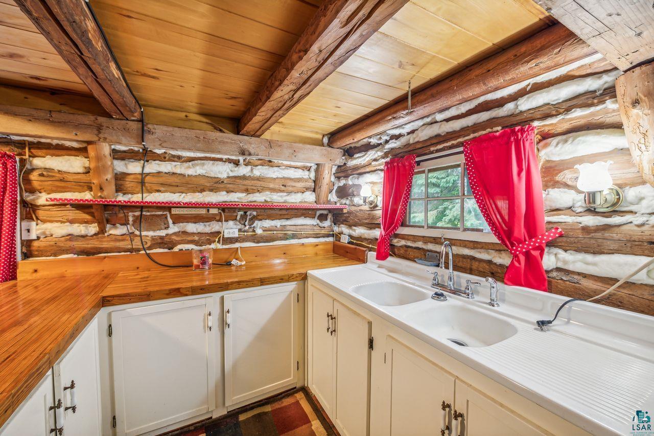 55675 Ashland Bayfield Road Mason, WI 54856 - Photo 7 of 26 Kitchen featuring beamed ceiling, wooden counters, wood ceiling, rustic walls, and sink