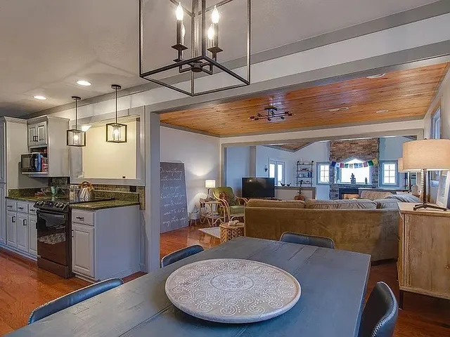 a view of a dining room with furniture a kitchen and chandelier