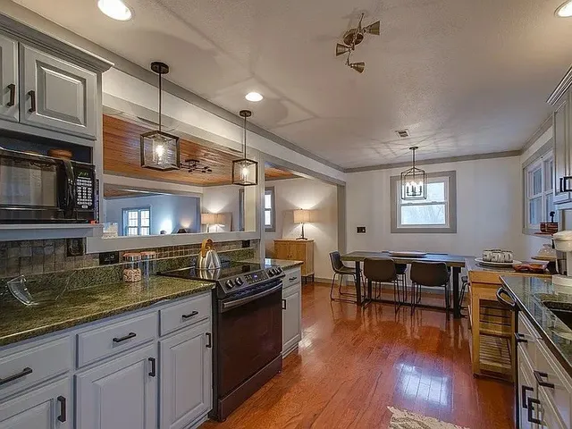 a kitchen with stainless steel appliances granite countertop wooden floors stove top oven and cabinets