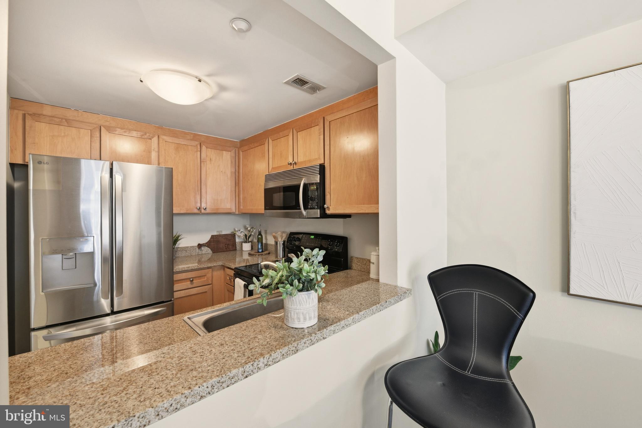 1150 K Street Northwest, Unit 1109 Washington, DC 20005 - Photo 8 of 33 a kitchen with stainless steel appliances granite countertop sink a refrigerator a stove a microwave oven with white cabinets and wooden floor