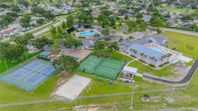 an aerial view of a tennis ground and a cars park side of the road