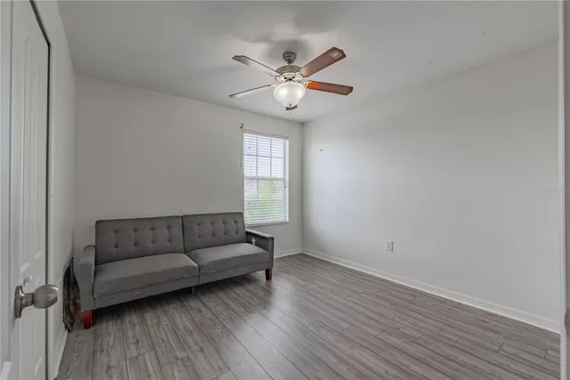 a view of empty room with wooden floor and fan