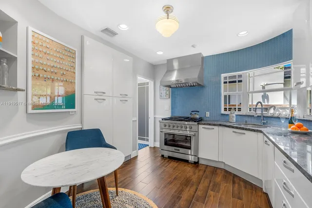 a kitchen with stainless steel appliances granite countertop a stove a sink a refrigerator cabinets and dining table