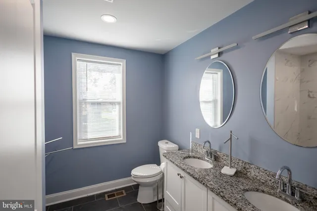a bathroom with a granite countertop toilet a sink and a mirror