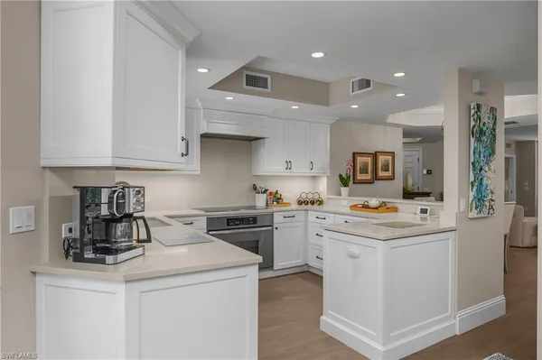 a kitchen with kitchen island a stove a sink a refrigerator and white cabinets