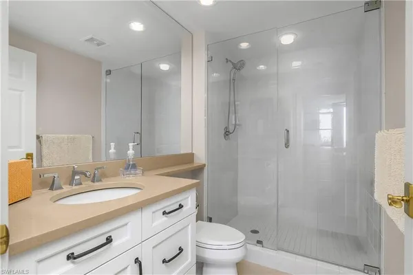 a bathroom with a granite countertop sink a toilet a mirror and shower
