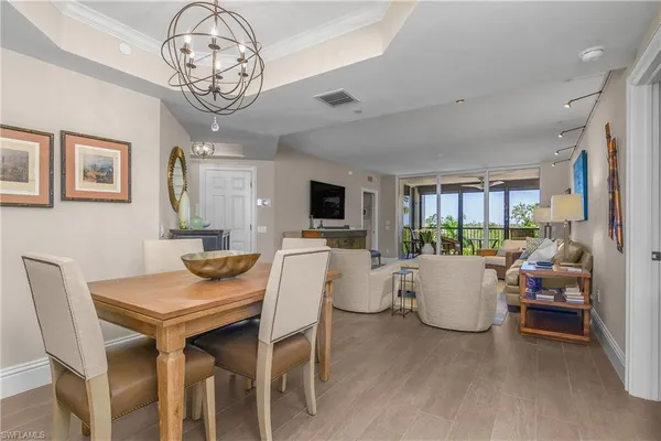 a view of a dining room with furniture a kitchen and chandelier