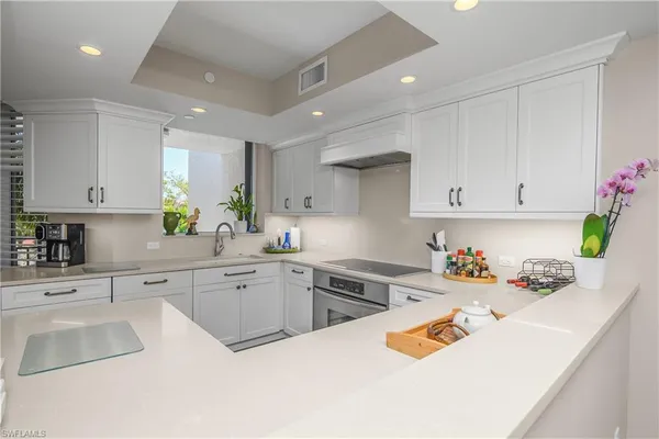 a kitchen with a sink dishwasher white stove and cabinets with wooden floor
