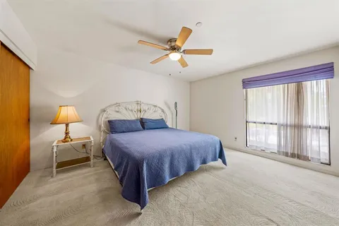 a bedroom with a bed chandelier and a large window
