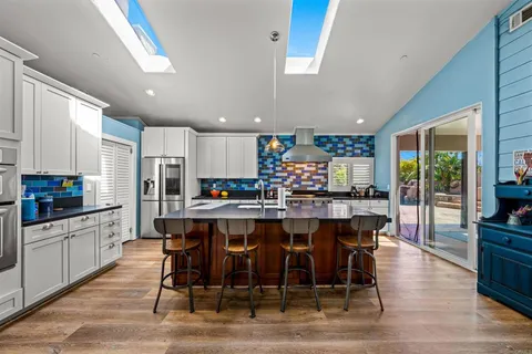 a kitchen with stainless steel appliances a dining table chairs and wooden floor
