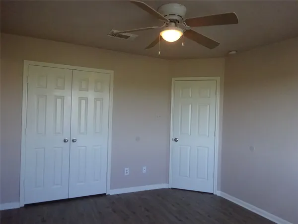 an empty room with closet and a ceiling fan