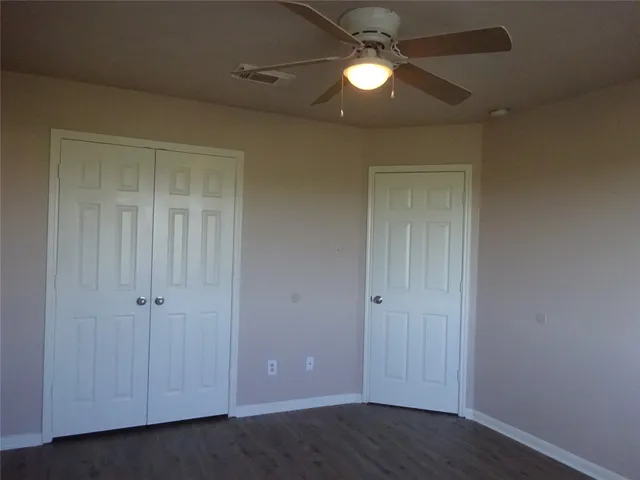 an empty room with closet and a ceiling fan