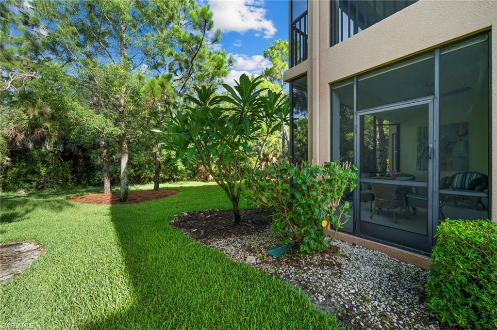 7837 Hawthorne Drive, Unit 1101 Naples, FL 34113 - Photo 32 of 41 a view of a backyard with potted plants and large tree