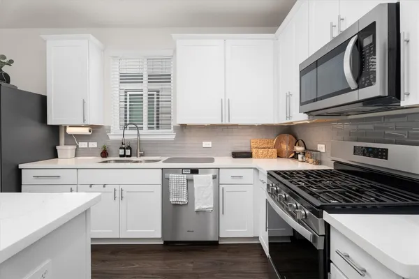 a kitchen with cabinets appliances a sink and a window