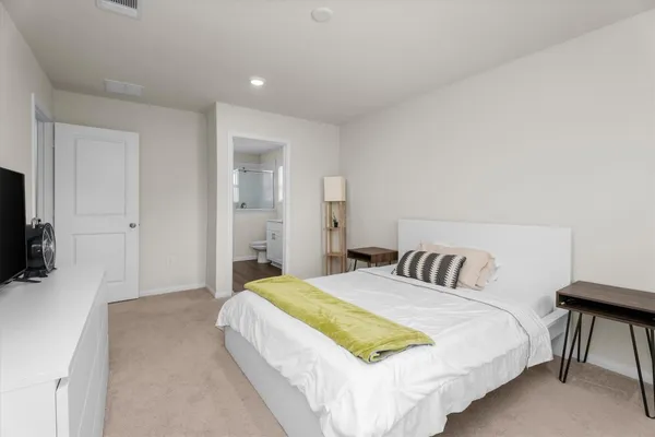 a bedroom with a bed and a flat tv screen on a dresser
