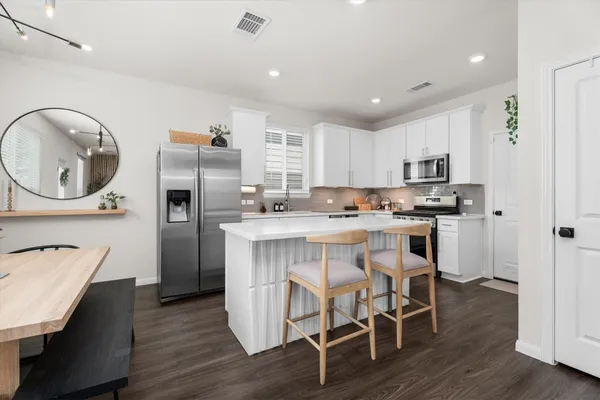 a kitchen with a dining table chairs refrigerator and cabinets