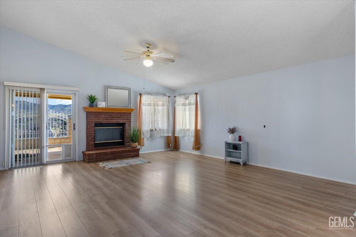 Undisclosed Address Tehachapi, CA 93561 - Photo 7 of 46 a view of empty room with fireplace wooden floor and fan