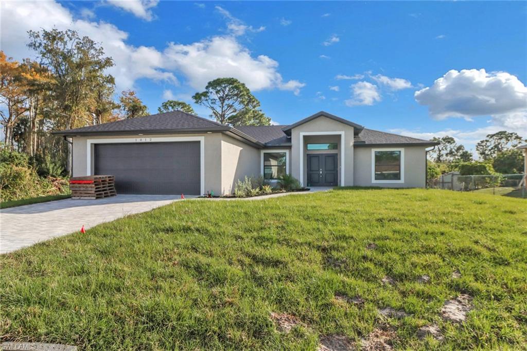 1012 Anza Avenue Lehigh Acres, FL 33971 - Photo 1 of 25 a front view of a house with a yard and garage