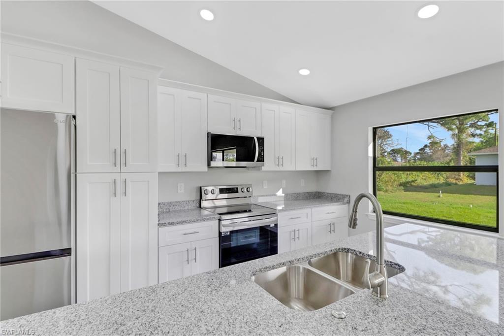 1012 Anza Avenue Lehigh Acres, FL 33971 - Photo 11 of 25 a kitchen with stainless steel appliances granite countertop a sink stove and refrigerator