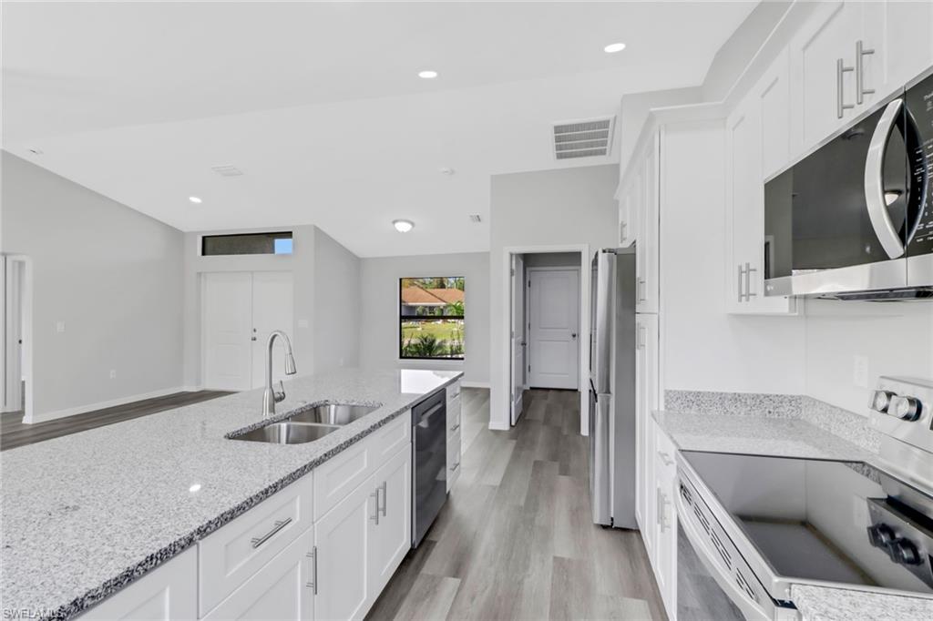1012 Anza Avenue Lehigh Acres, FL 33971 - Photo 12 of 25 a kitchen with a sink dishwasher a stove and a refrigerator with wooden floor
